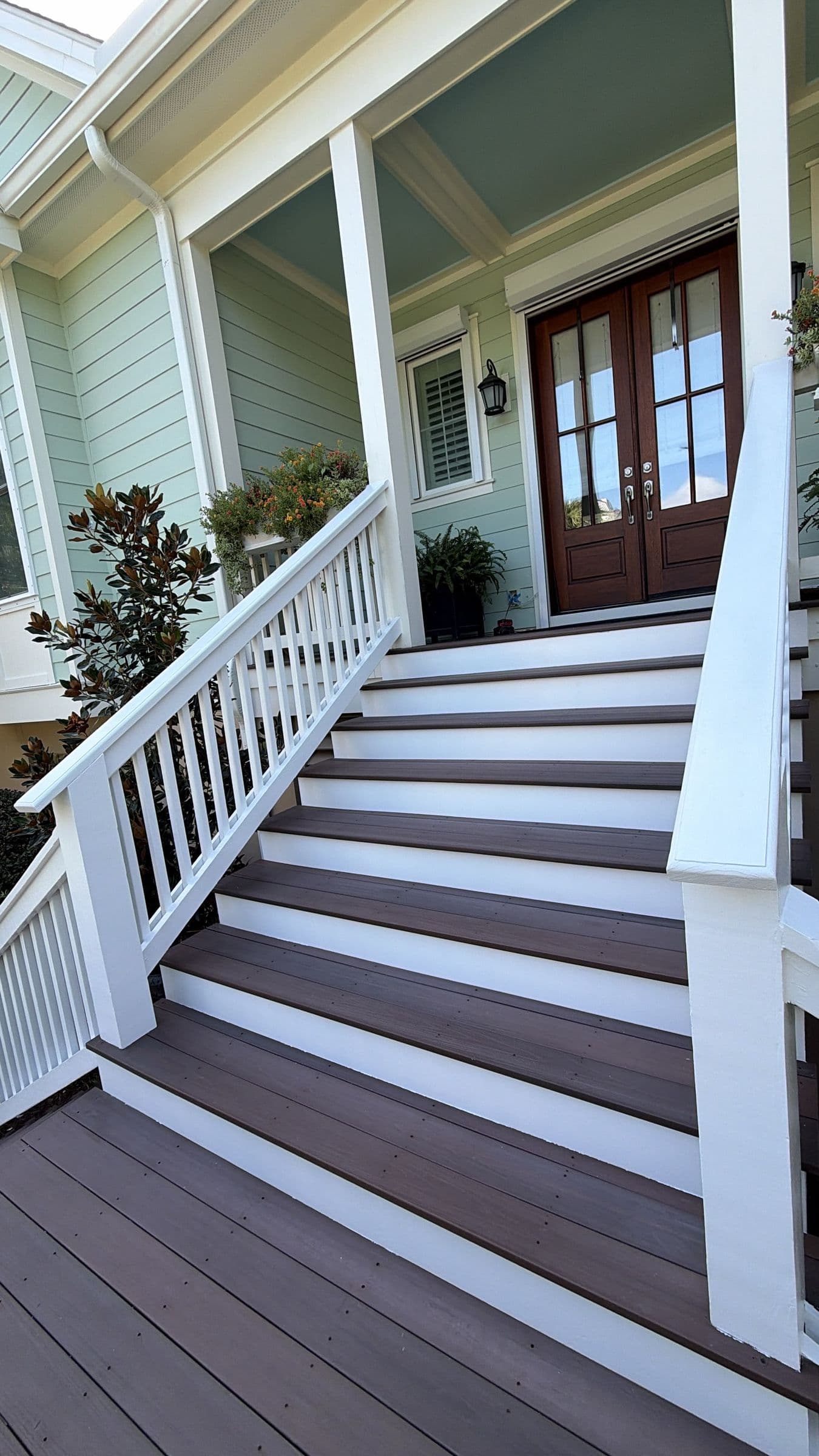 Front entry stair with composite treads and white rails up to mahogany double doors