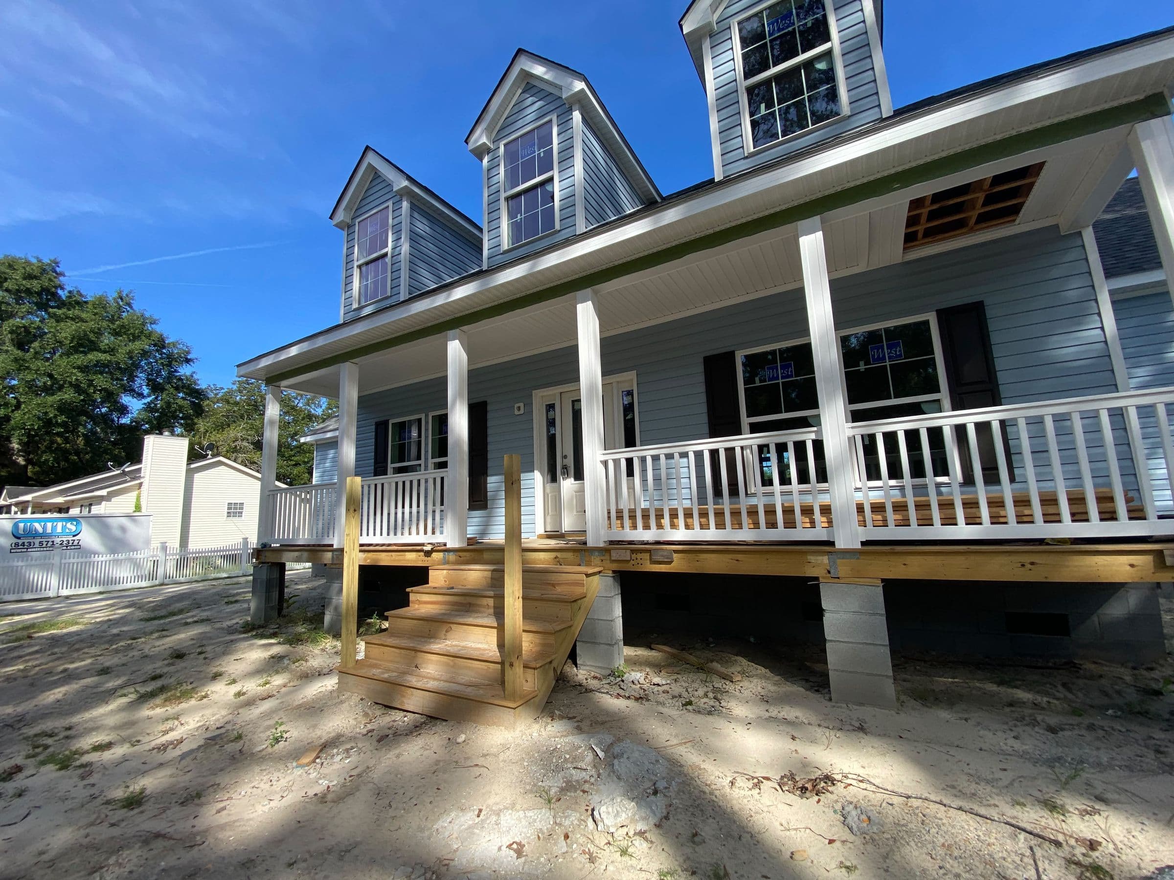 Wraparound front porch with white rails on a new farmhouse