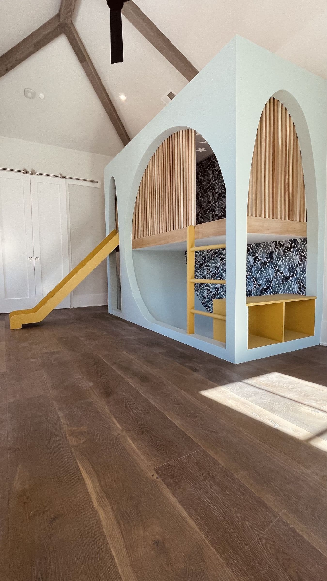 Built-in arched playhouse loft with a slide in a vaulted room