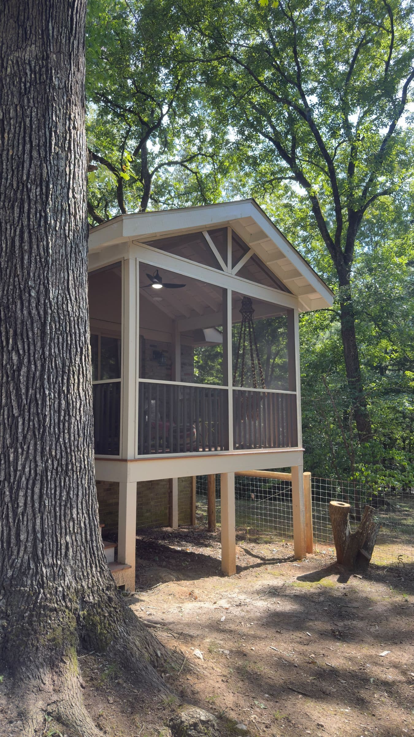 Screened porch addition raised on posts under the trees